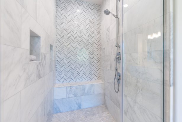 Walk-in shower with white and gray pattern tile, overhead rain s